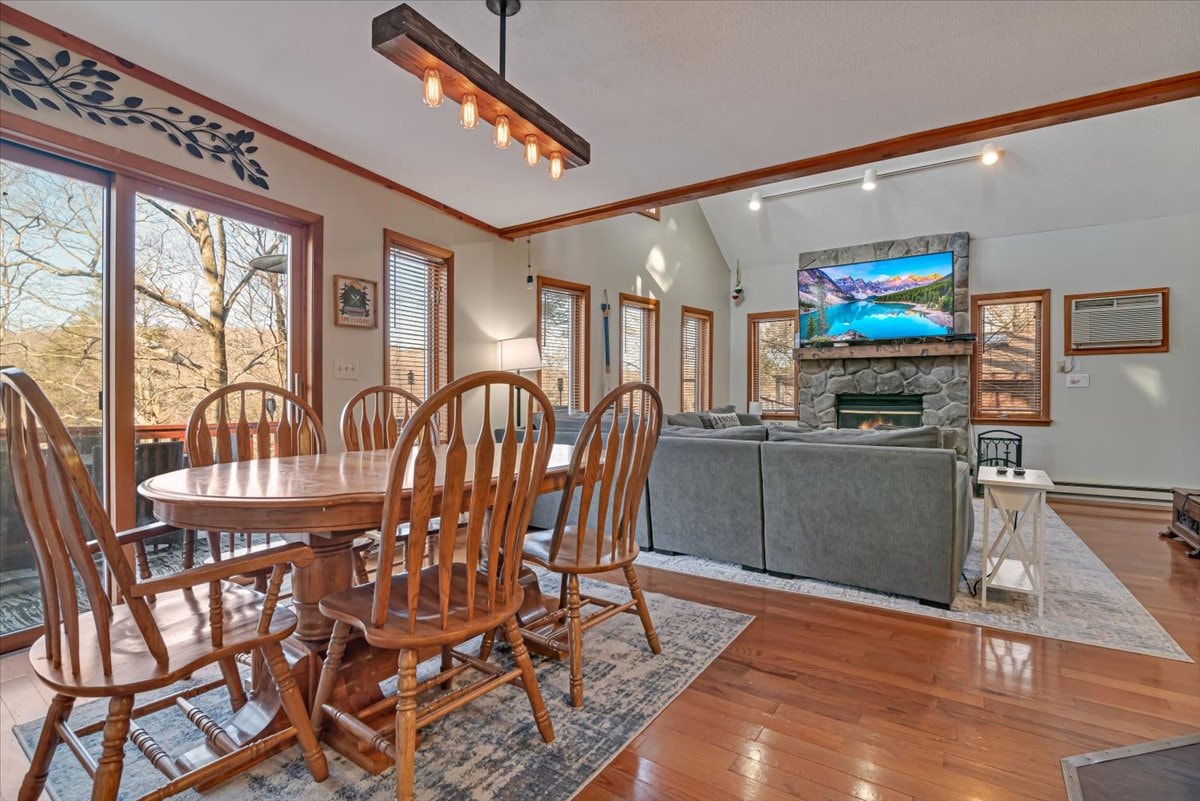 Open concept dining and living room with stone fireplace and hardwood floors