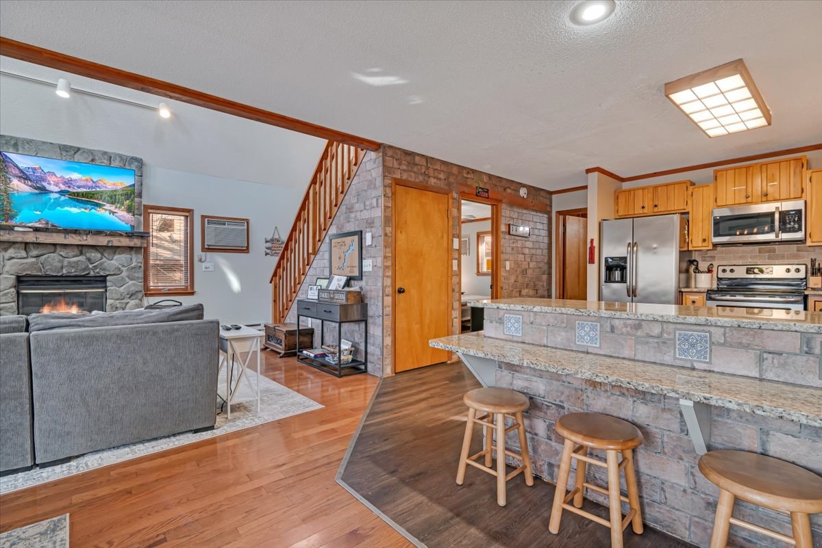 Open concept kitchen and living room with stone fireplace and staircase