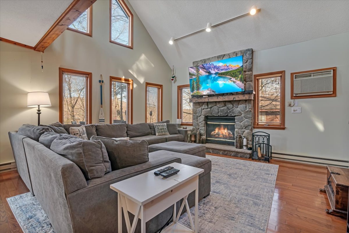 Vaulted living room with stone fireplace, sectional sofa and cathedral windows