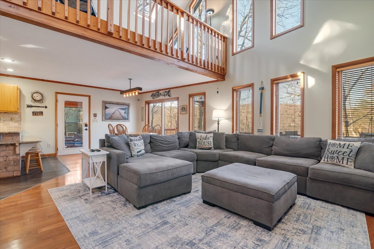Spacious living room with large sectional, loft balcony and lake house decor