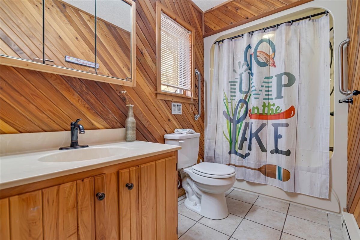 Rustic bathroom with cedar wood paneling and lake-themed shower curtain