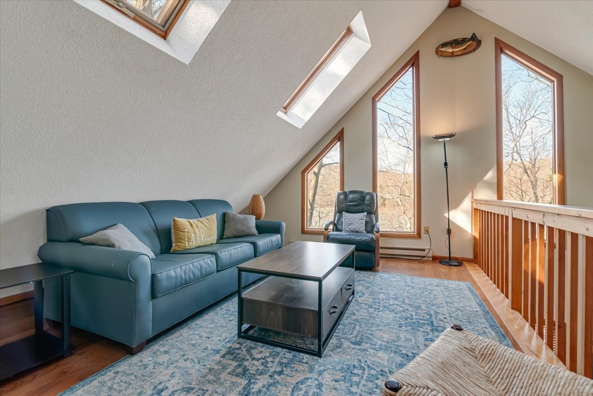 Loft sitting area with teal sofa, skylights and large angled windows
