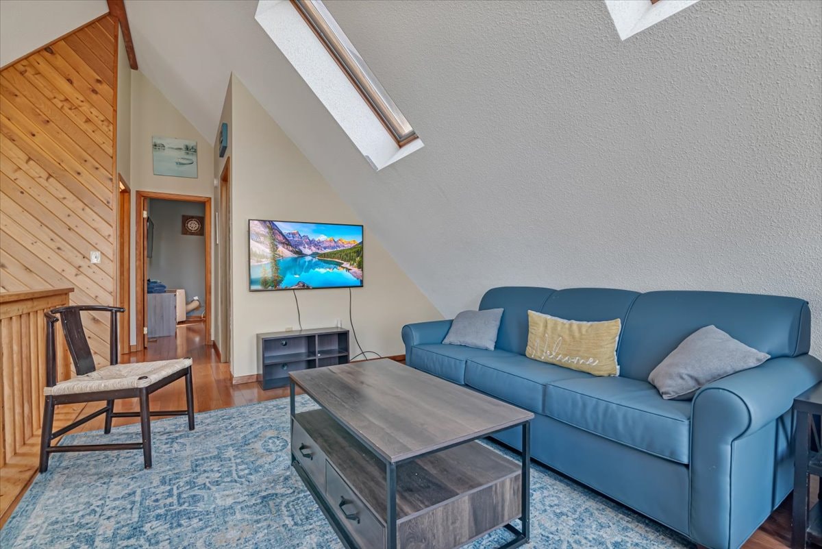 Loft TV room with blue sofa, wall-mounted TV and skylight