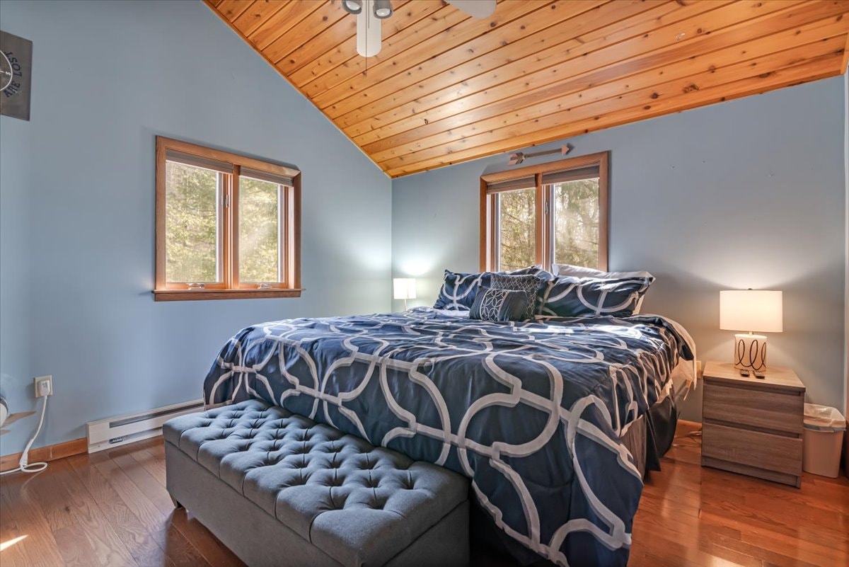 Master bedroom with king bed, blue bedding and pine wood ceiling