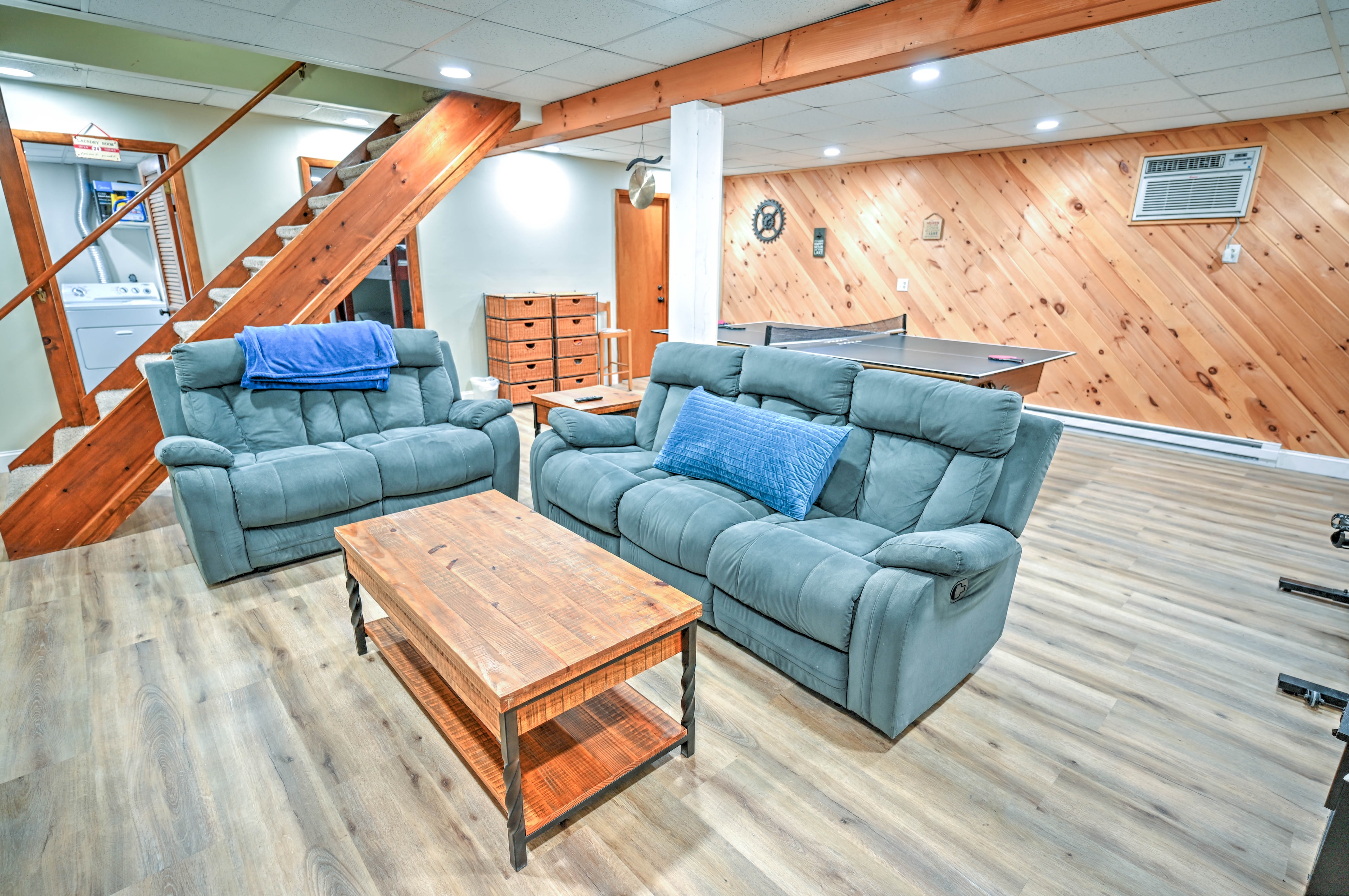 Basement game room with blue recliner sofas, wood beam and ping pong table