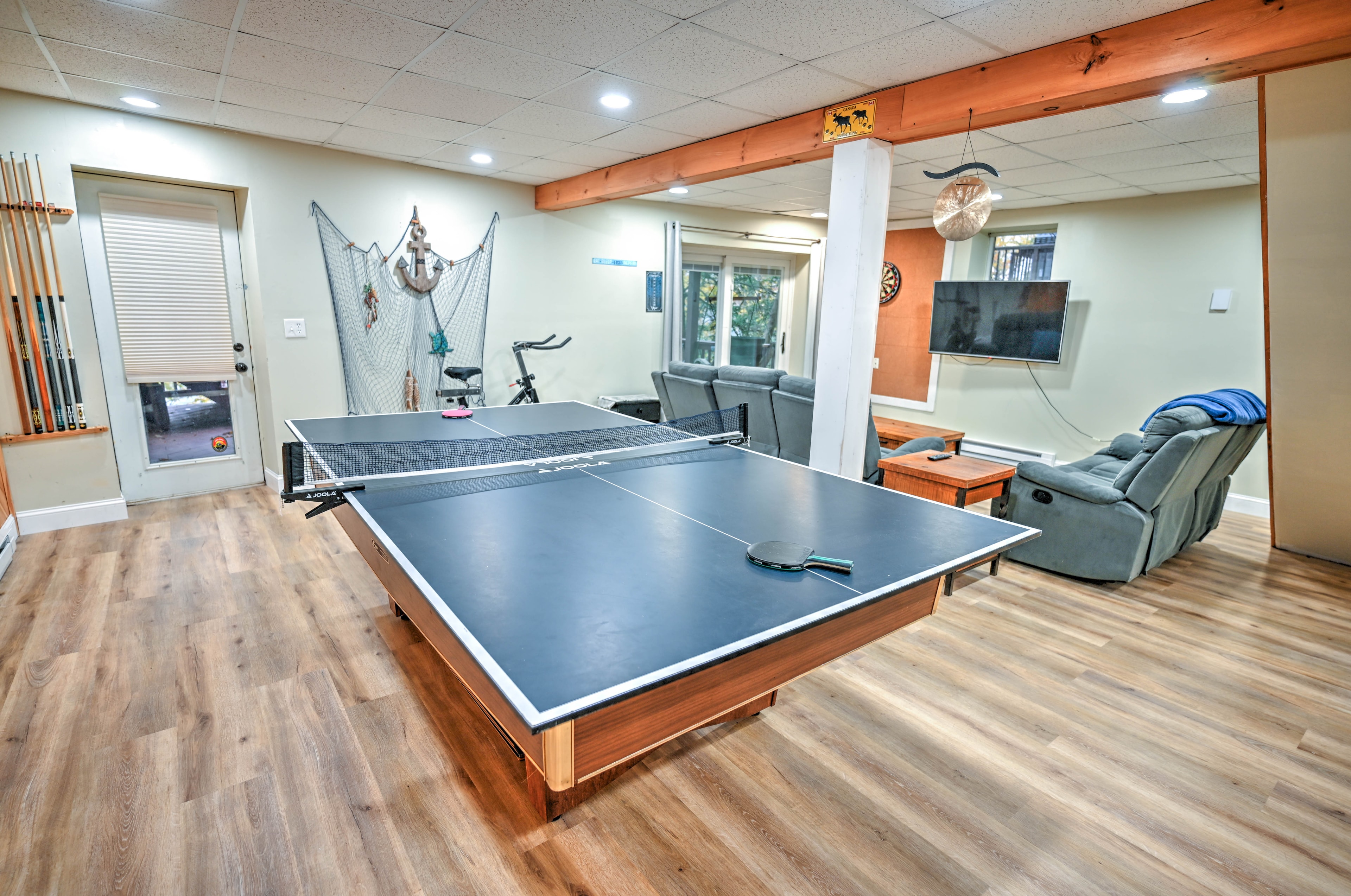 Game room with ping pong table, pool cues, exercise bike and nautical decor