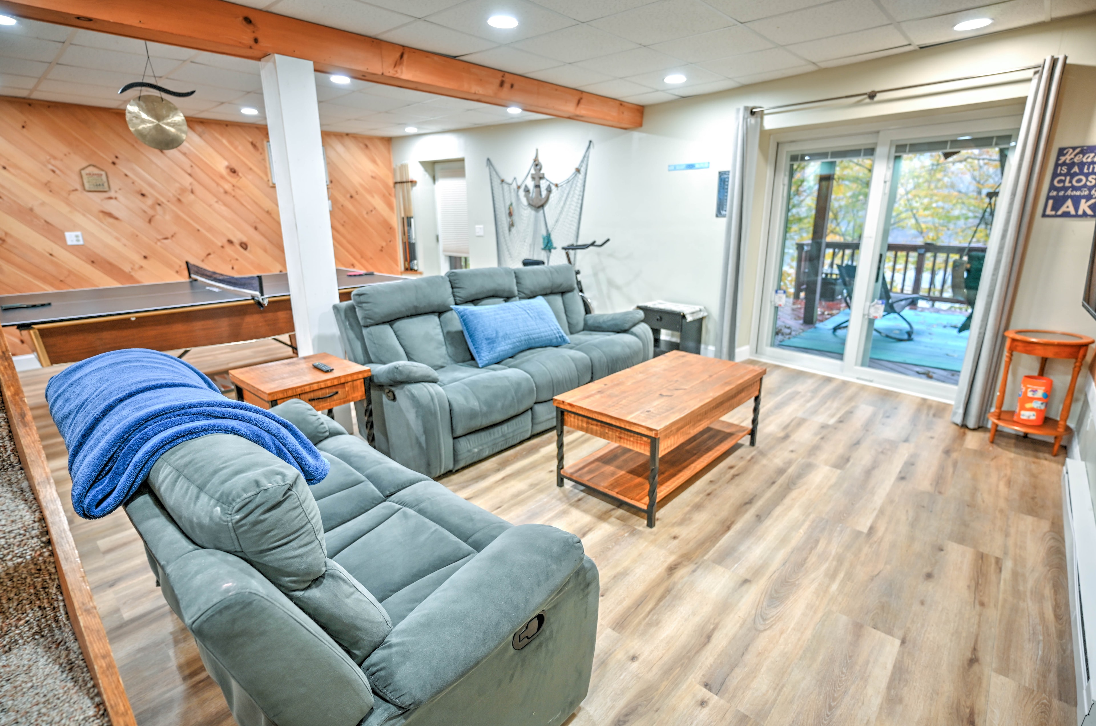 Game room with blue recliner sofas, coffee table and lake views through sliding doors