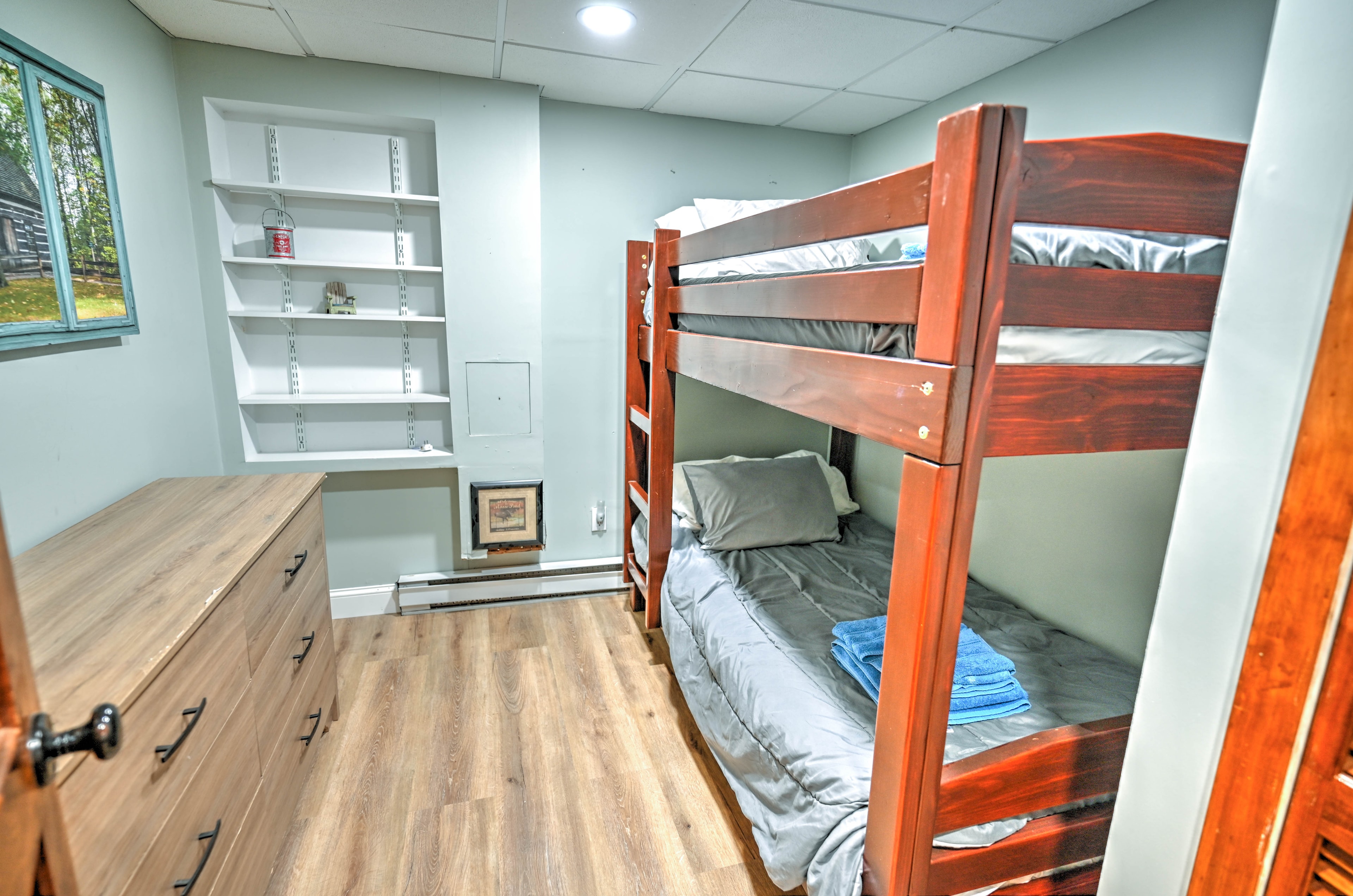 Basement bedroom with twin-over-twin bunk bed, dresser and built-in shelving
