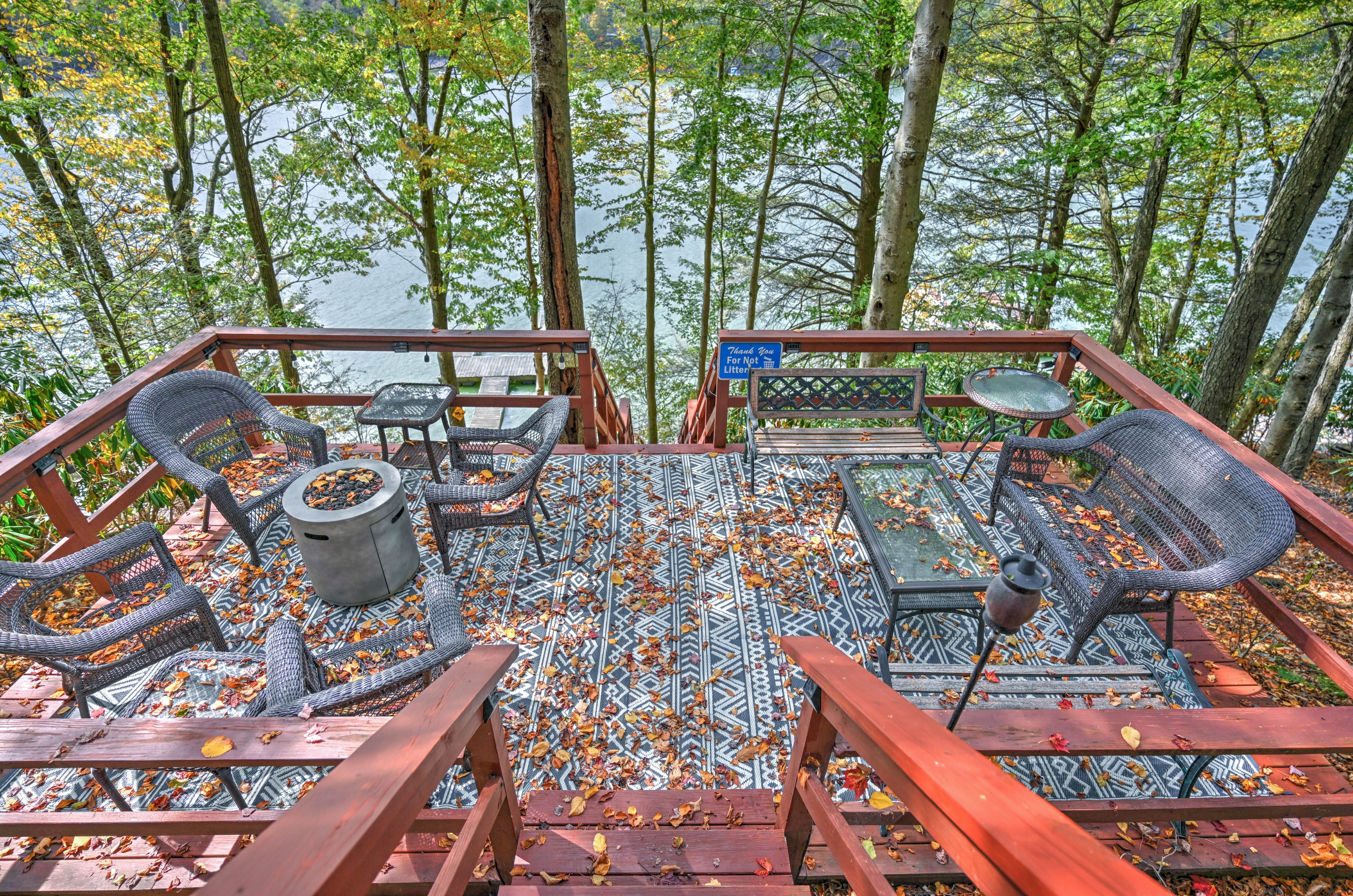 Lakeside deck with wicker chairs, fire pit and fall foliage framing the water