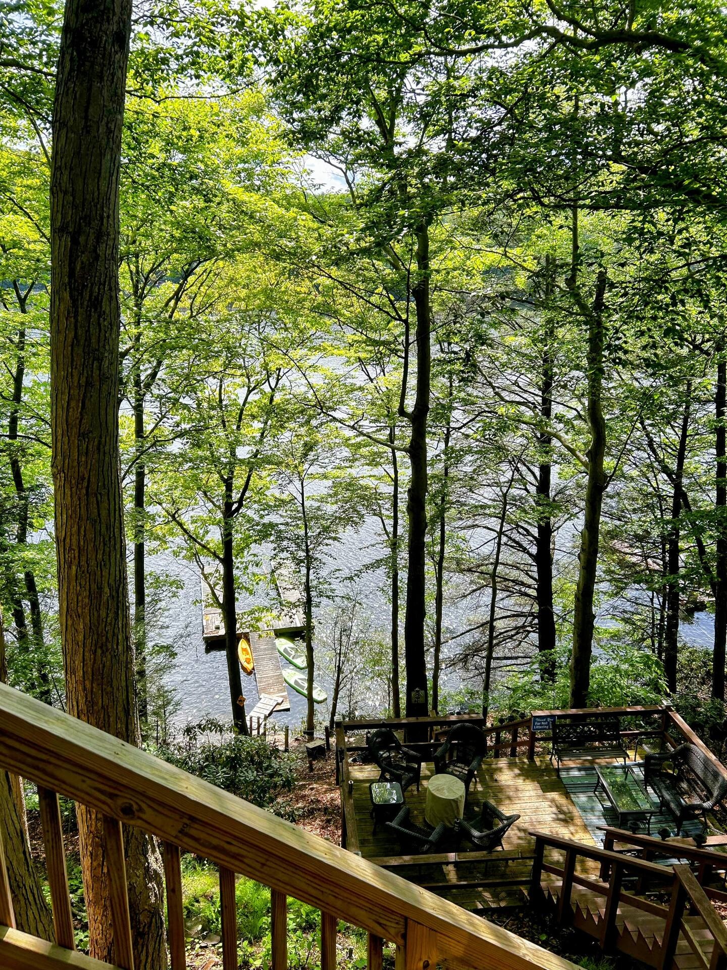 View from upper deck down to dock and kayaks on Lake Wallenpaupack through summer trees